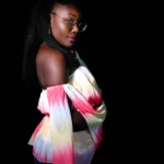 shooting photo studio sur fond noir un jean bleu avec un haut coloré épaule dégagées